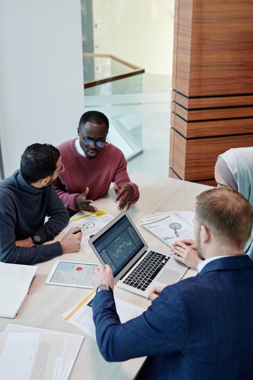 Free A diverse group of professionals collaborating in an office setting with laptops and documents. Stock Photo