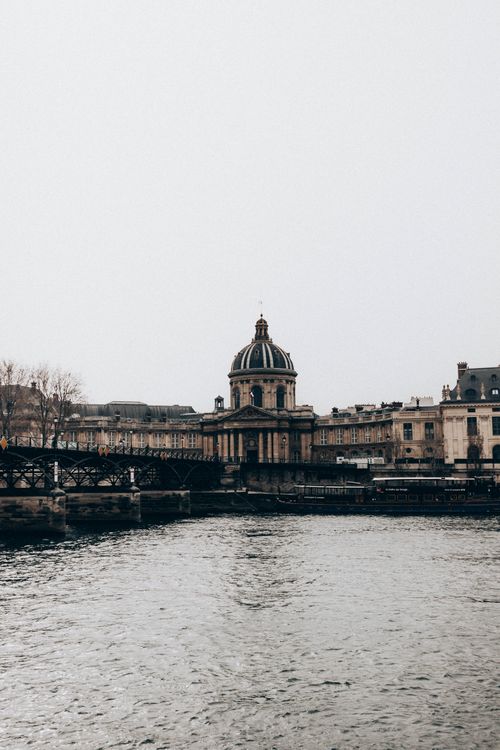 Free Aged institute facade with columns against bridge above Seine River under light sky in Paris France Stock Photo