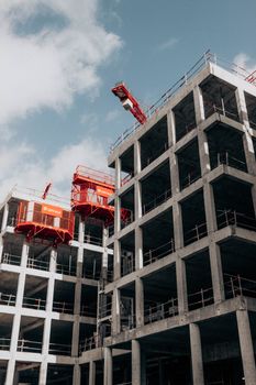 From below process of construction of new modern multistory building under cloudy blue sky in city
