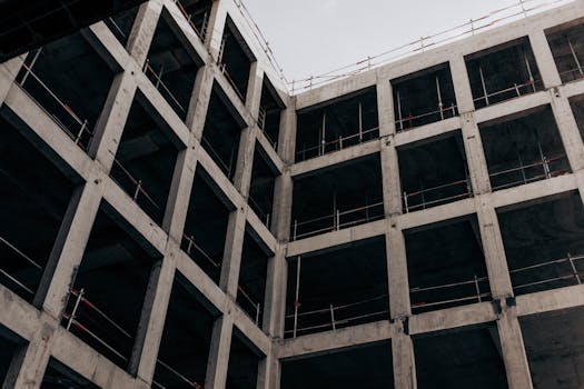 A low angle view of a modern concrete building under construction, showcasing its structure and design.