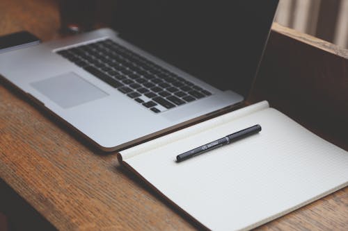 Macbook Pro Beside White Book