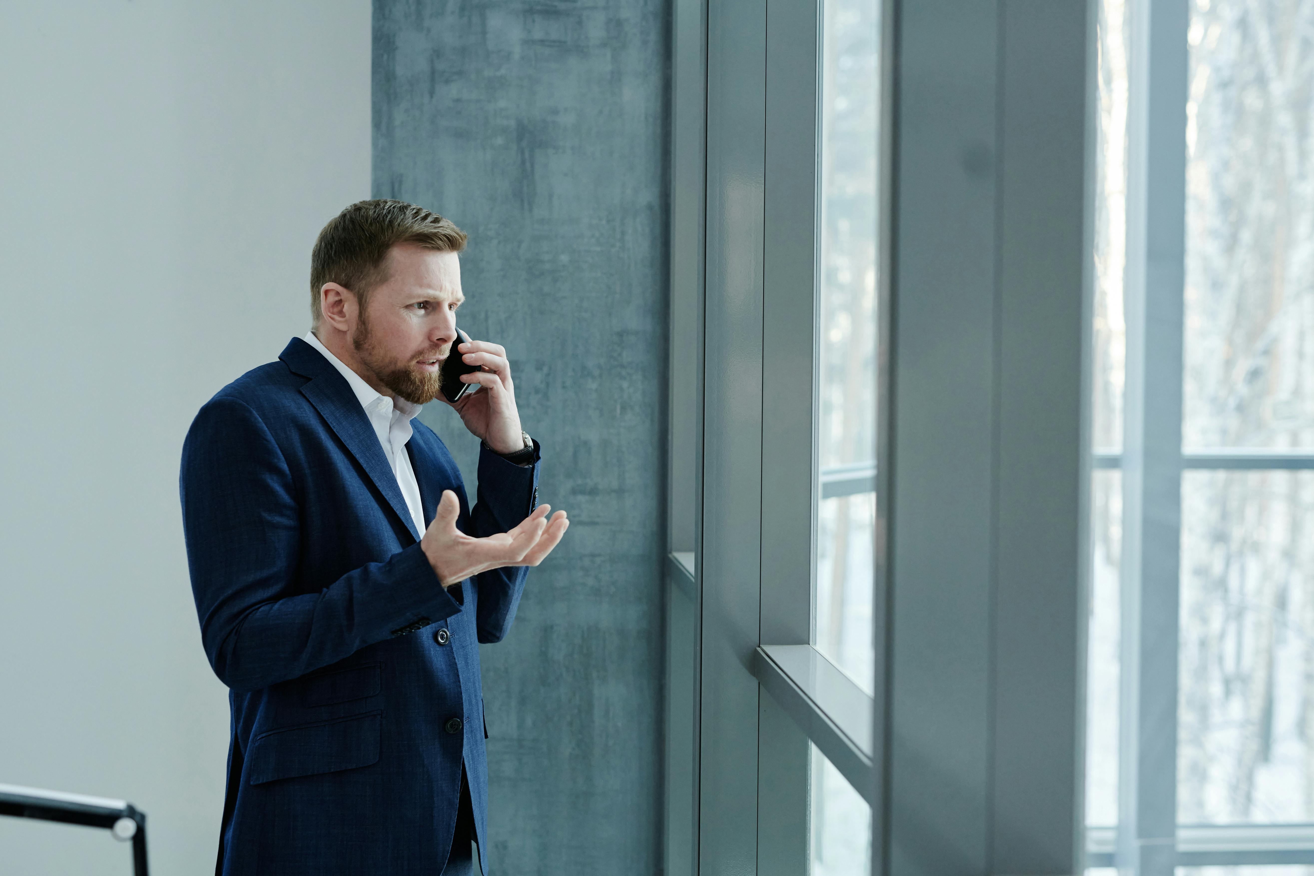 man in blue suit jacket standing near glass window