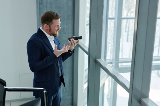 Businessman in a blue suit expressing frustration during a phone call.