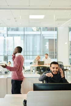 Dynamic office environment featuring diverse professionals engaged in teamwork and multitasking on phone calls.