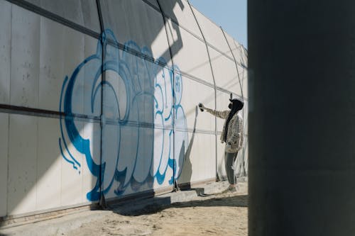 Side View Photo of Person Doing Graffiti on Wall