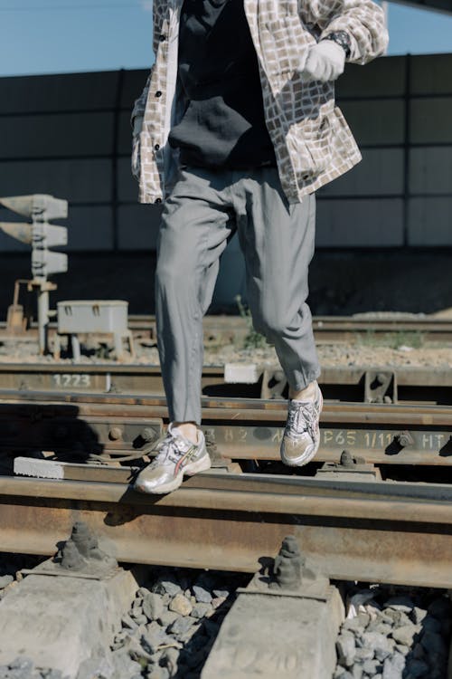 Free A Person Wearing Pants and Rubber Shoes Stepping on Railroad Tracks Stock Photo