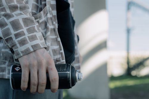 Free Close-up of a person holding a spray paint can, outdoors in an urban environment. Stock Photo