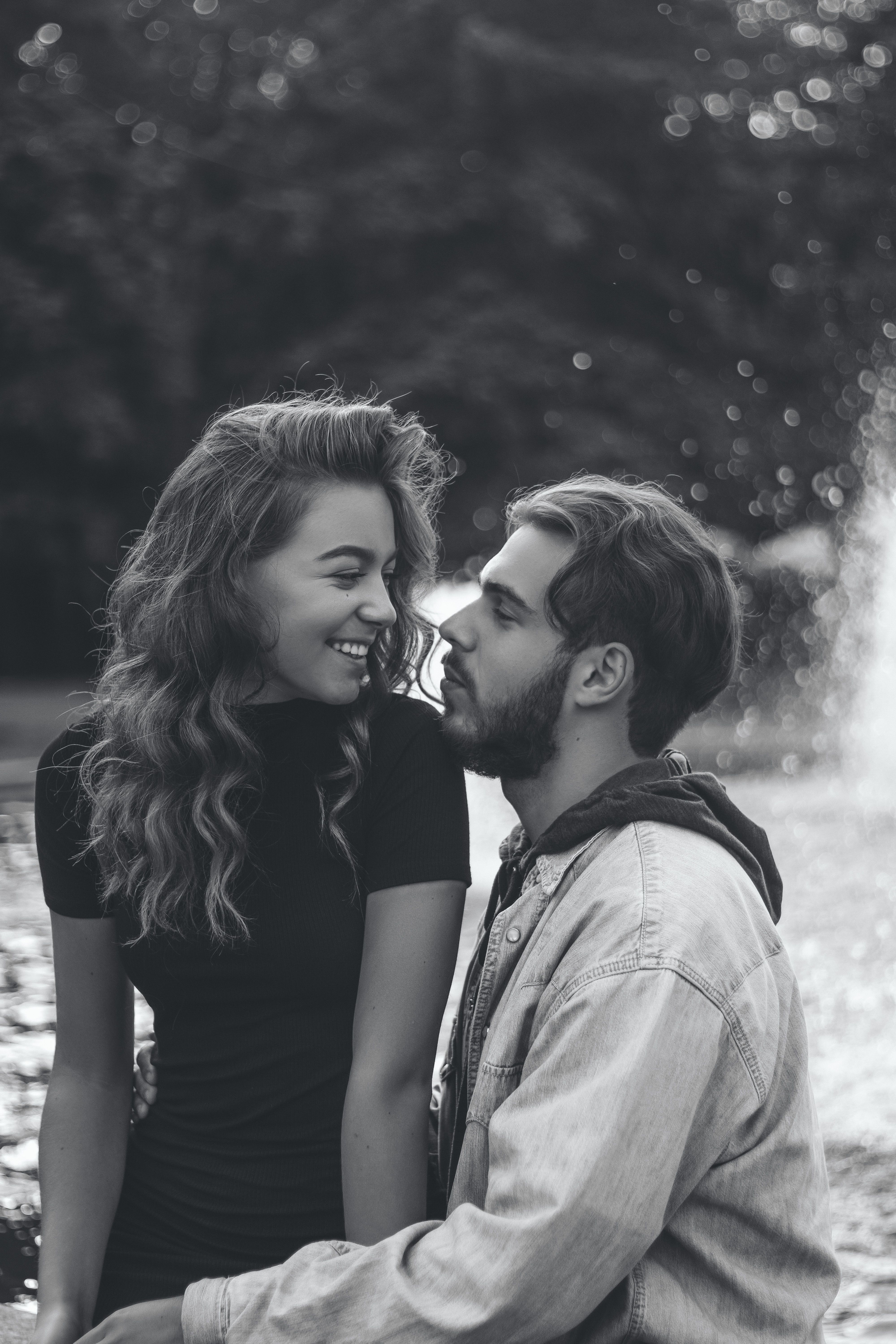 A romantic couple embracing by a fountain, captured in a classic black and white portrait.
