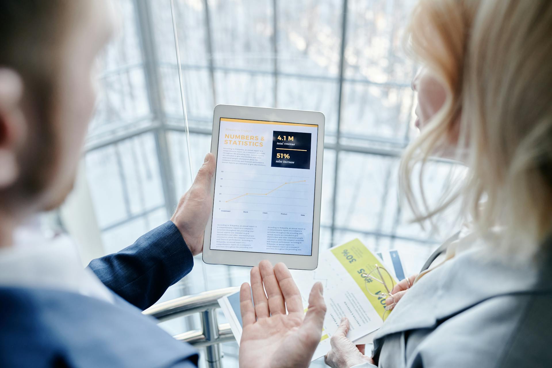 Business professionals discussing analytics on a tablet in a modern office setting.