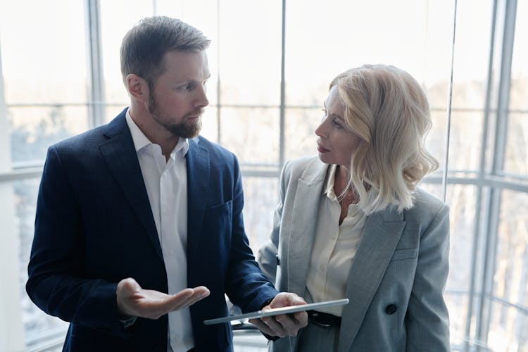 A Man Holding A Tablet While Communicating With A Woman