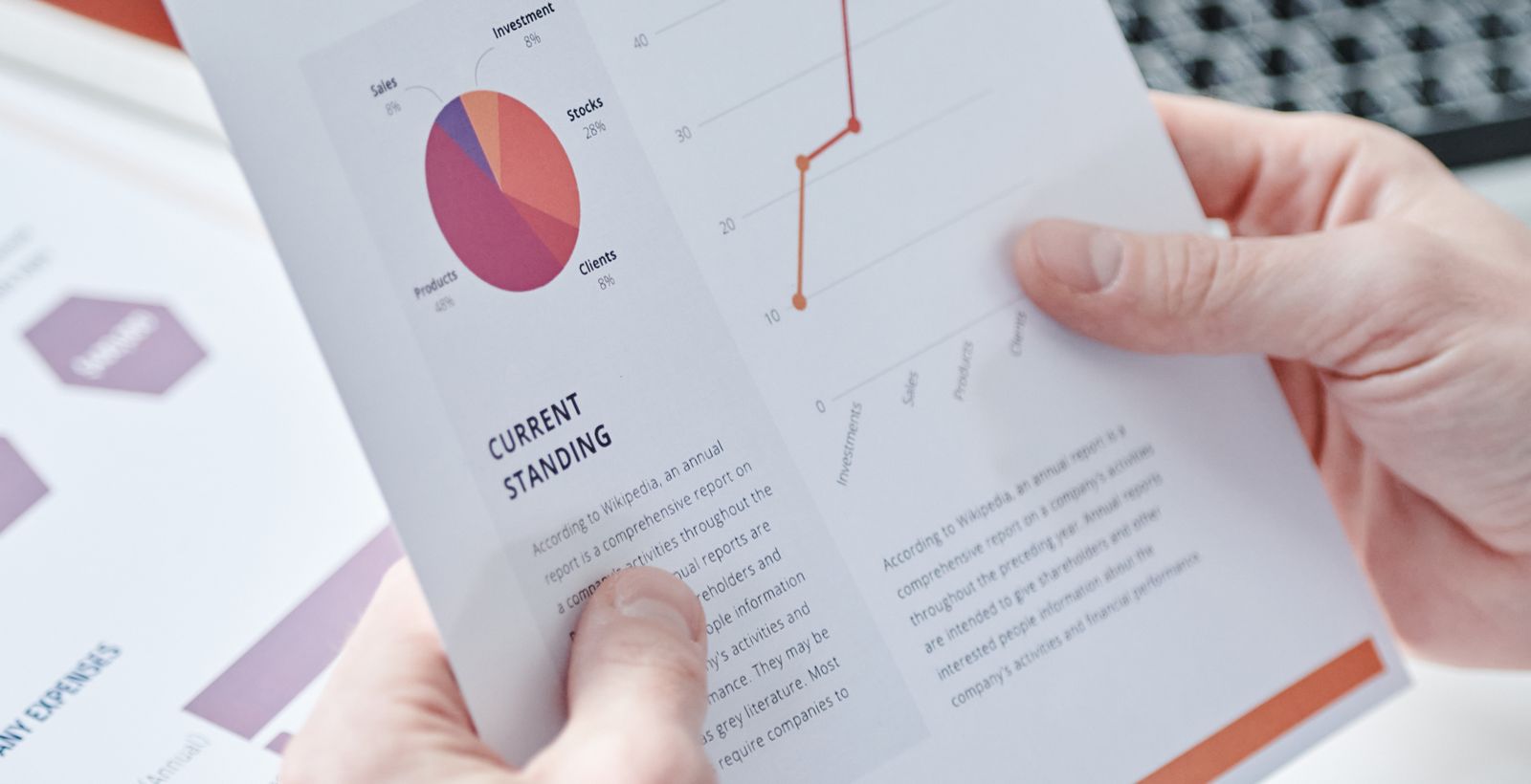 A person holding a printed report of pie and line charts