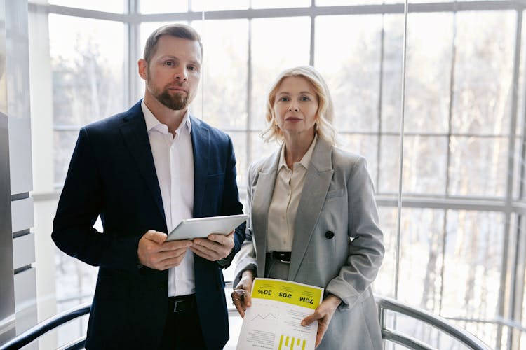 Man Holding A Tablet And Woman Holding Documents Standing 