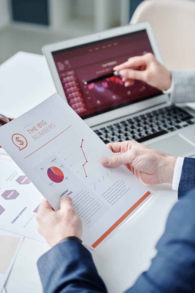 Person Holding Document With A Person Showing Laptop