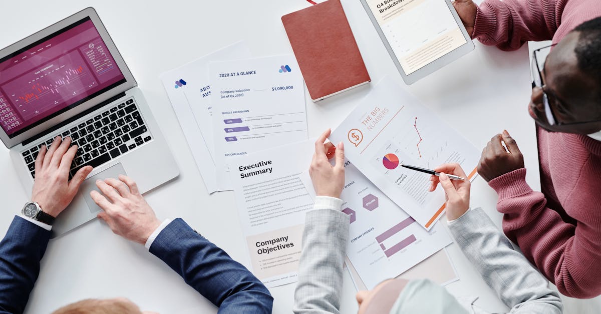Top view of a diverse team collaborating on digital devices and papers in an office setting.