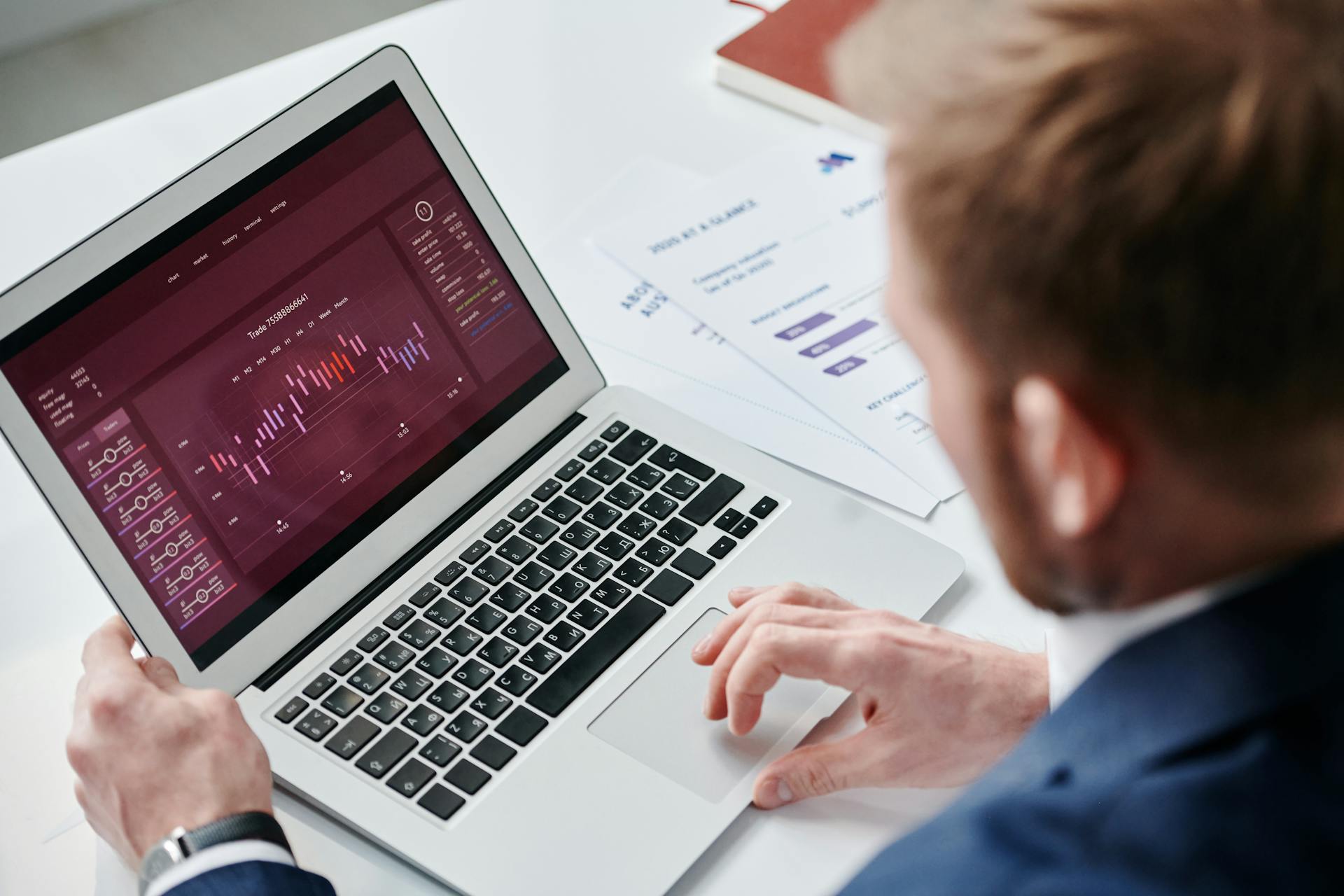 Businessman reviewing data analytics dashboard on laptop in bright office.