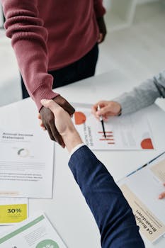 Professional handshake over financial documents symbolizes successful business partnership and teamwork.