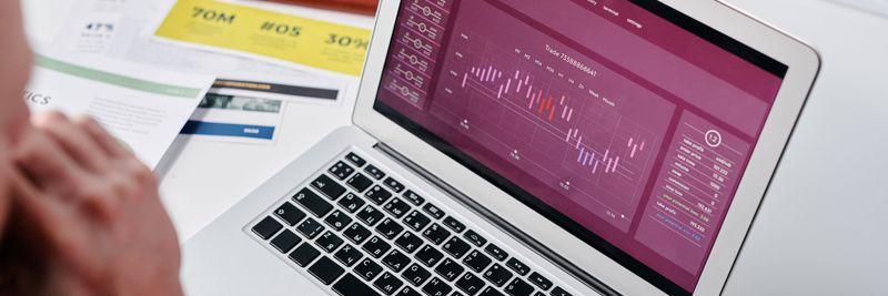 Businessperson reviewing data analytics on a laptop screen in an office setting.