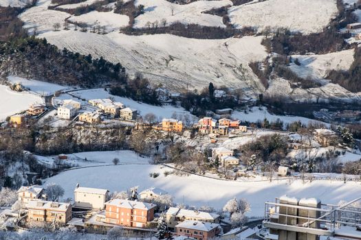 Aerial view of a snow-covered town in San Marino showcasing charming buildings and winter scenery.
