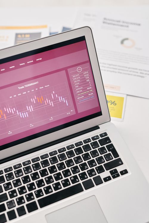 High angle view of a laptop displaying analytics graphs beside printed SEO reports