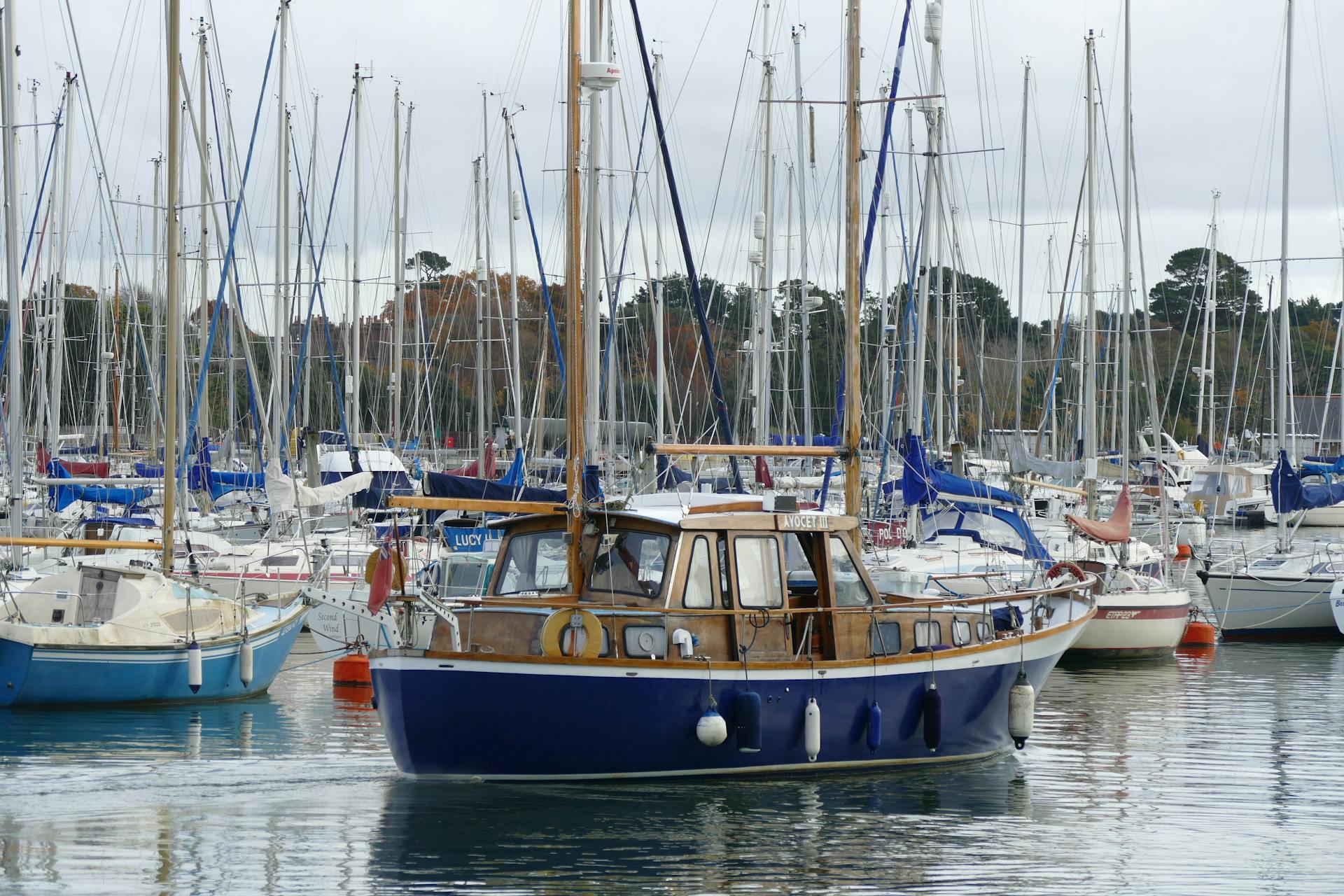 A variety of sailboats and yachts docked at Lymington Marina in England, captured on a cloudy day.