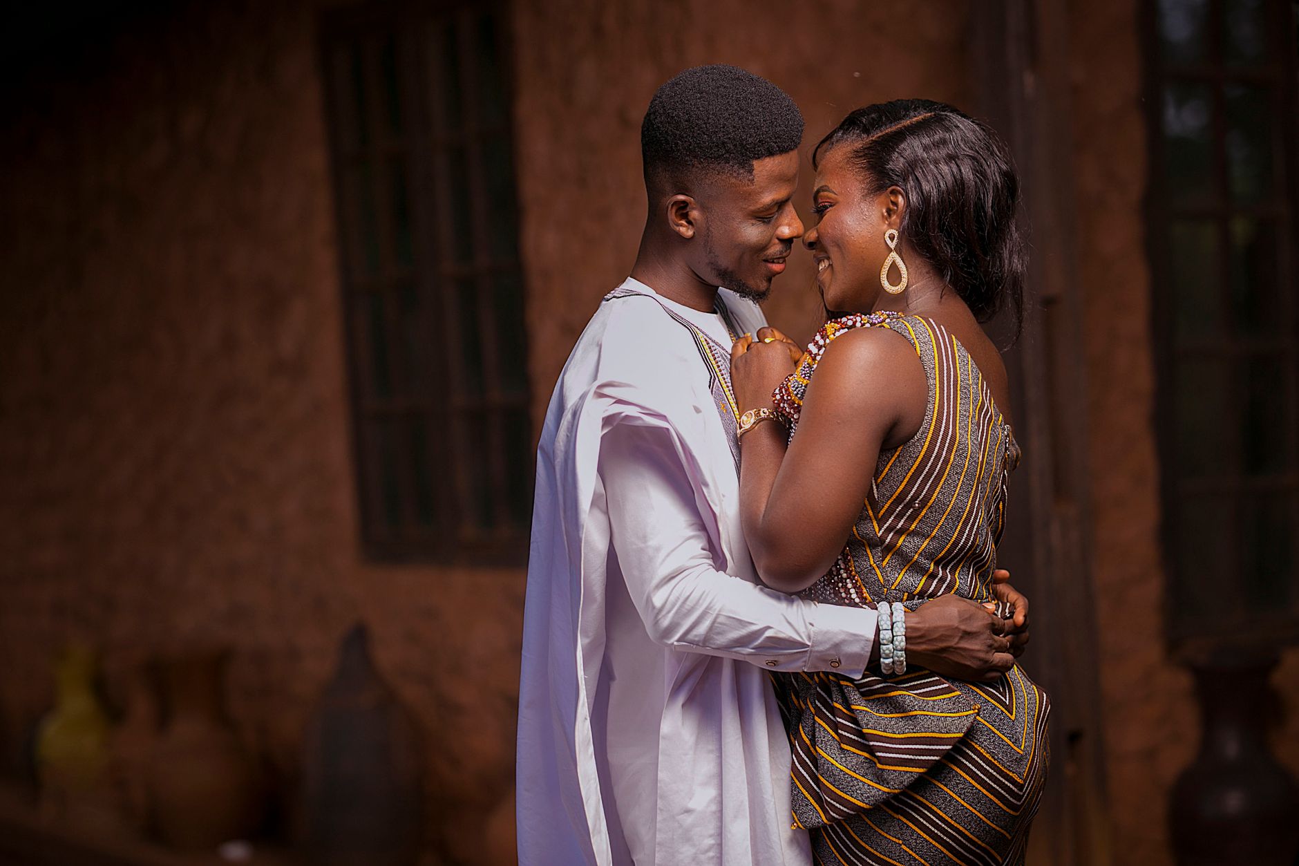 A loving couple embracing in traditional Ghanaian attire, expressing romance and joy.