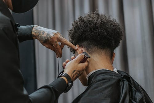 Free Back View of a Man with Curly Hair Getting His Hair Shaved Stock Photo