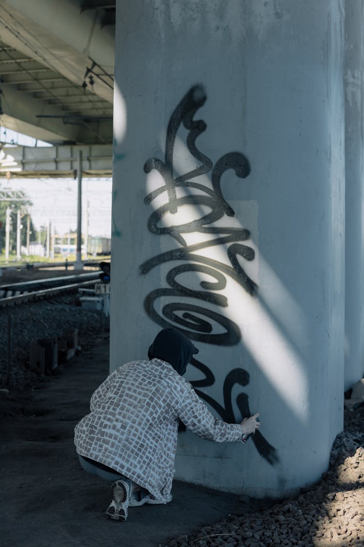 A Person Painting Graffiti In A Concrete Post