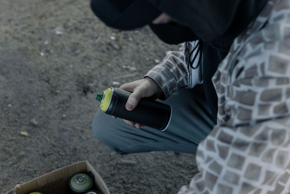 Cabinet Painting Lafayette CO: True Factory Finish in 2026 2 A graffiti artist holding a spray paint can outdoors, preparing to create street art.