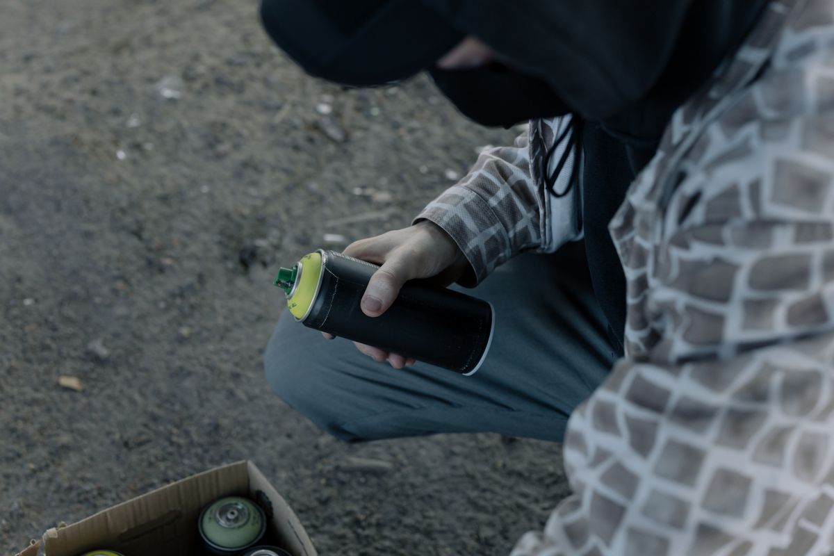 A graffiti artist holding a spray paint can outdoors, preparing to create street art