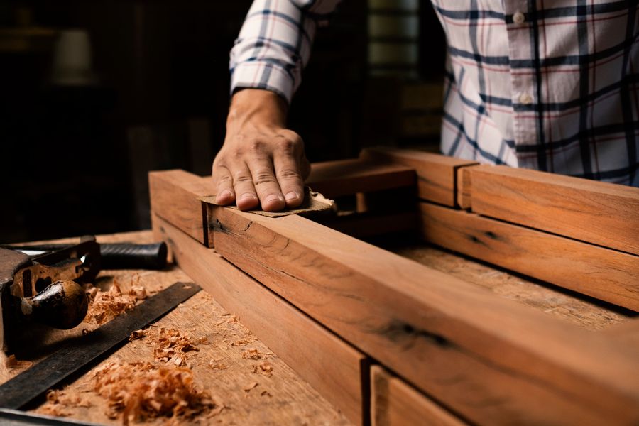 Hands smoothing a wooden frame with abrasive paper