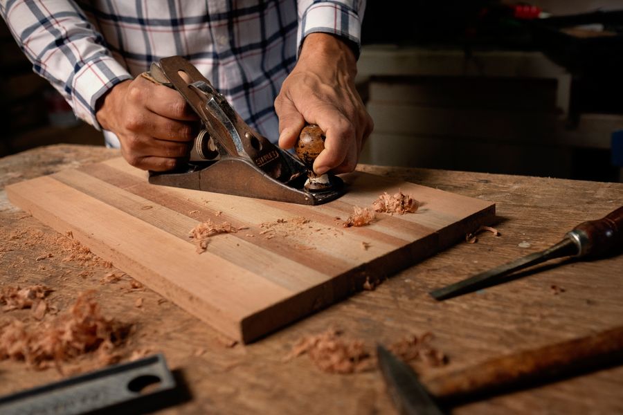 A hand plane taking a shaving off a prepared board