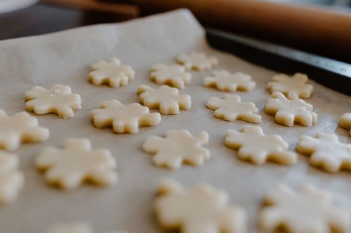 Free Raw snowflake-shaped cookie dough arranged on parchment paper, ready for baking. Stock Photo