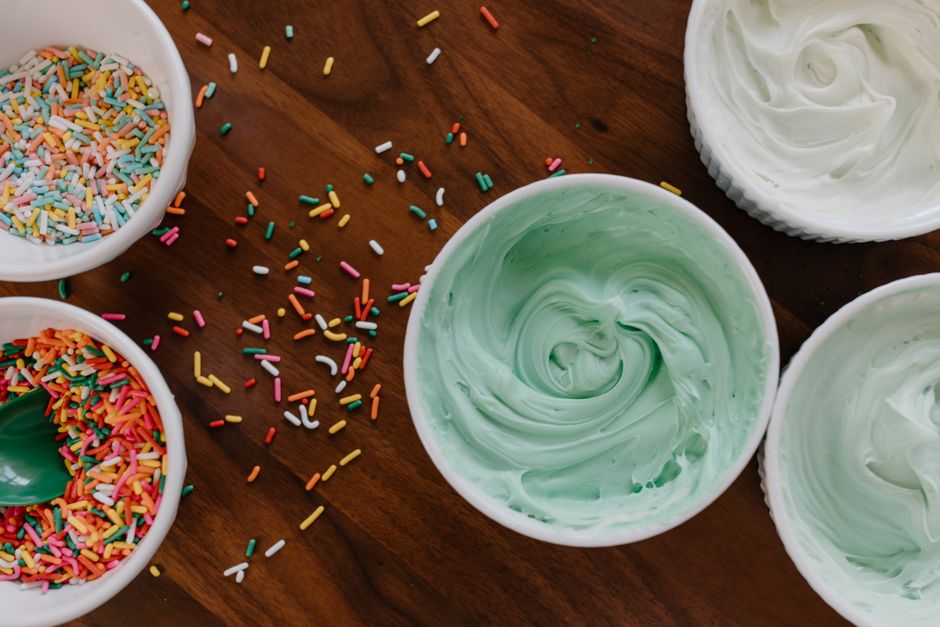 A cake layer covered in smooth, matte ermine frosting with piped rosettes showing its silky, whipped-cream-like texture