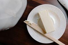 A stick of butter on a speckled plate with a wooden knife — photo by Tara Winstead on Pexels