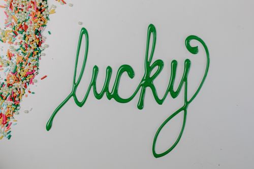 Free Green icing spells 'lucky' with colorful sprinkles on a white background. Stock Photo