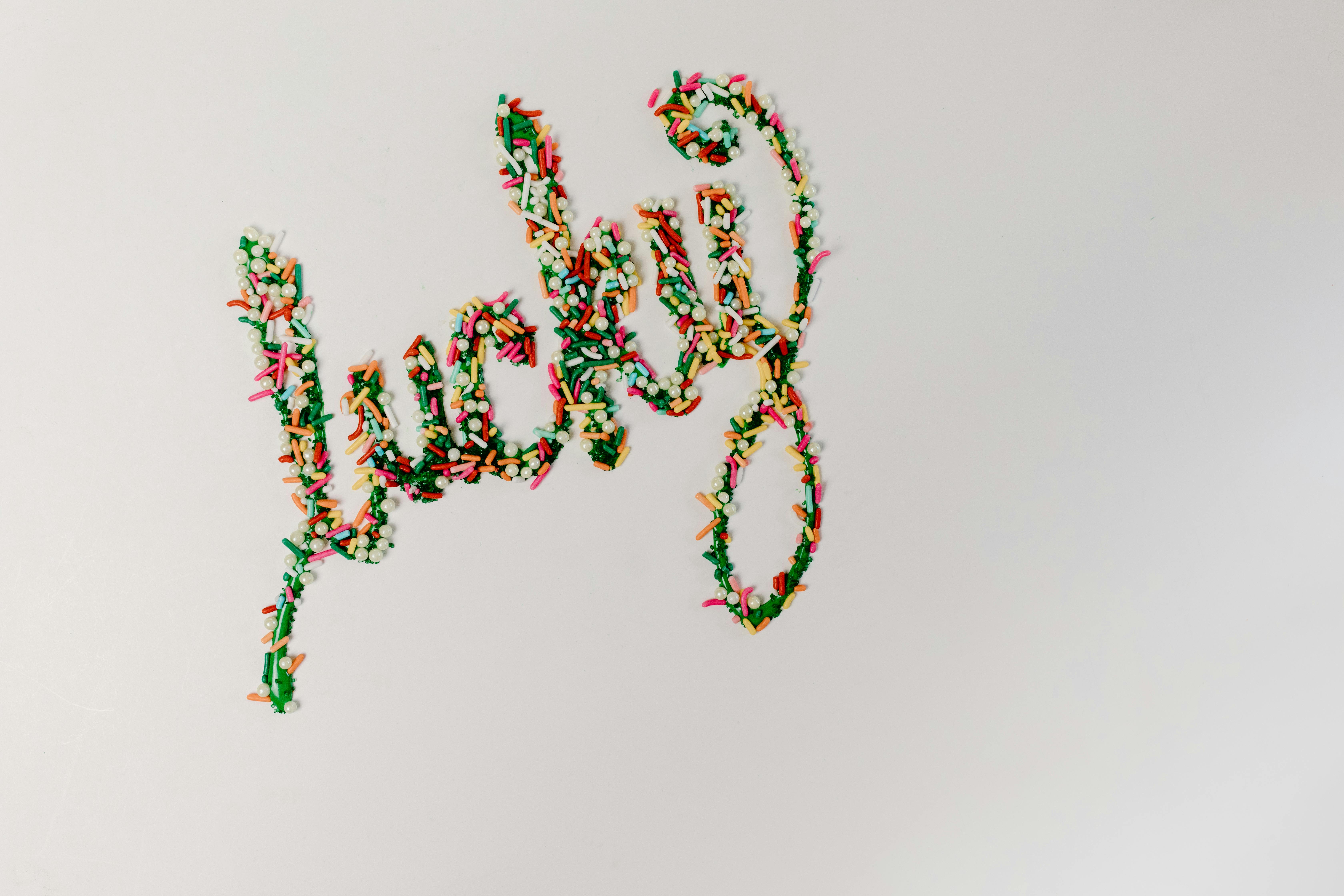 Colorful sprinkles arranged in the word 'lucky' on a white background, offering a fun and festive design.