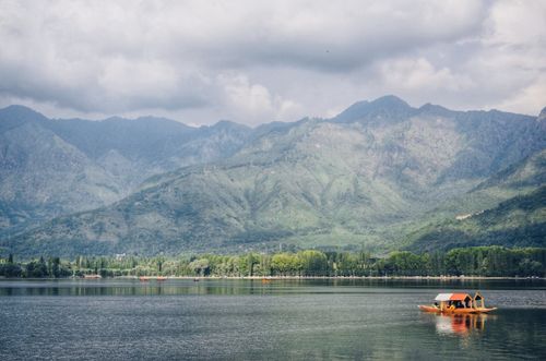 Free Idyllic mountain lake scene featuring a traditional boat and lush green mountains. Stock Photo