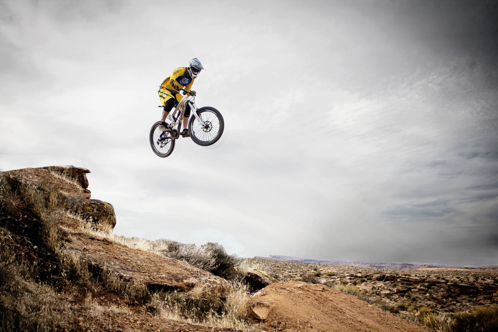 Mountain biker riding a bright rocky trail with protective gear