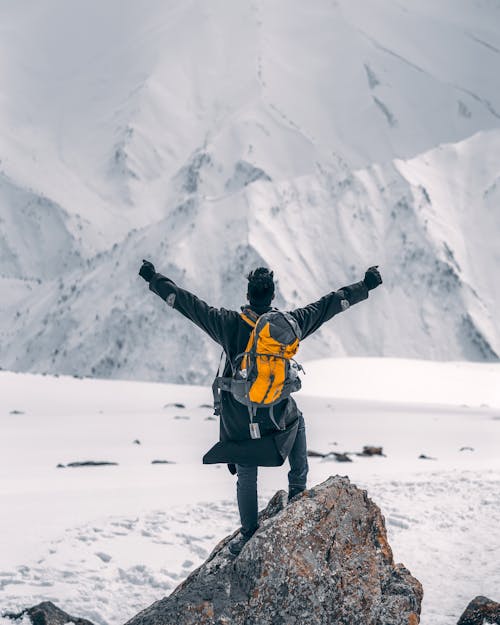 Man With Arms Outstretched Standing on Mountain Peak