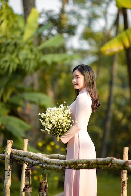 Woman in White Dress Holding Bouquet of Flowers