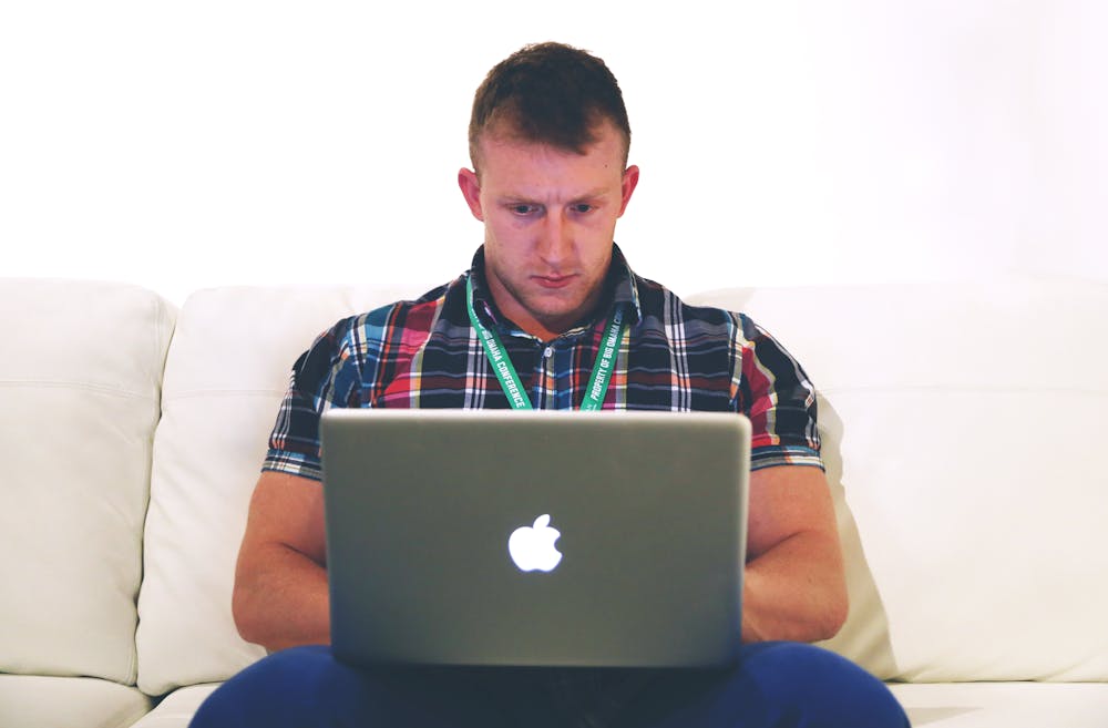 Man using macbook while sitting on sofa | Photo: Pexels