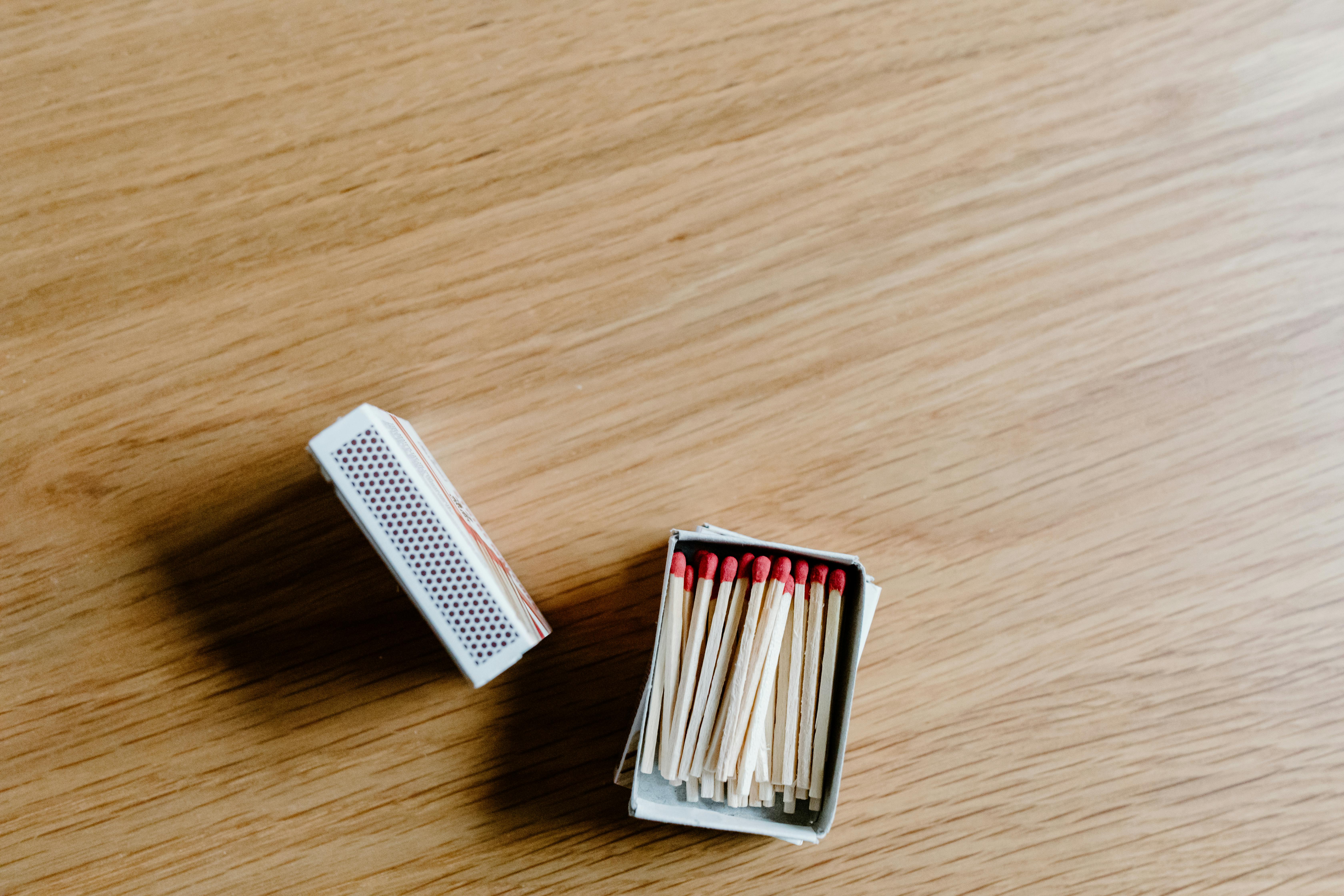 A close-up of an open matchbox with matchsticks on a wooden surface.