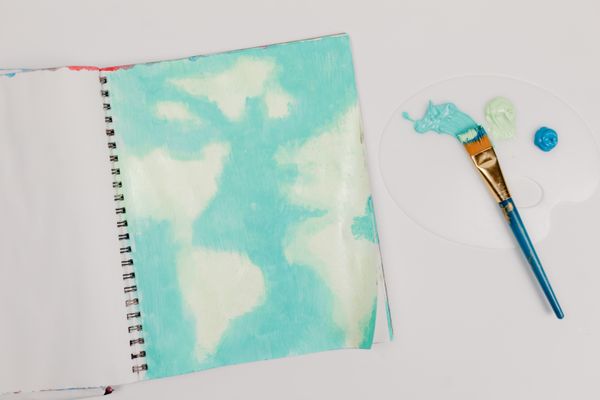 Sketchbook page with a soft watercolour wash and a brush. Photo by Tara Winstead on Pexels