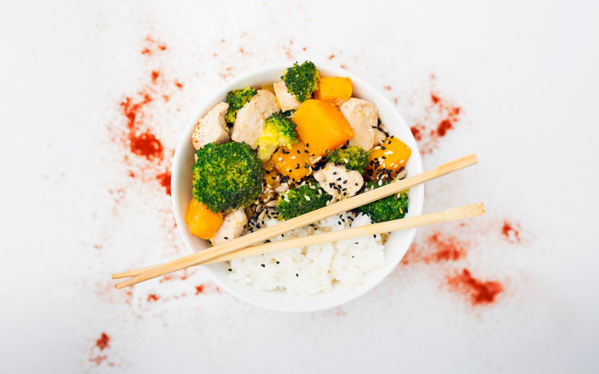 A delicious Asian-inspired chicken bowl with vegetables, rice, and spices.