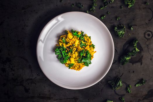 A colorful curry dish with kale on a white plate, shot from above. Perfect for food lovers.