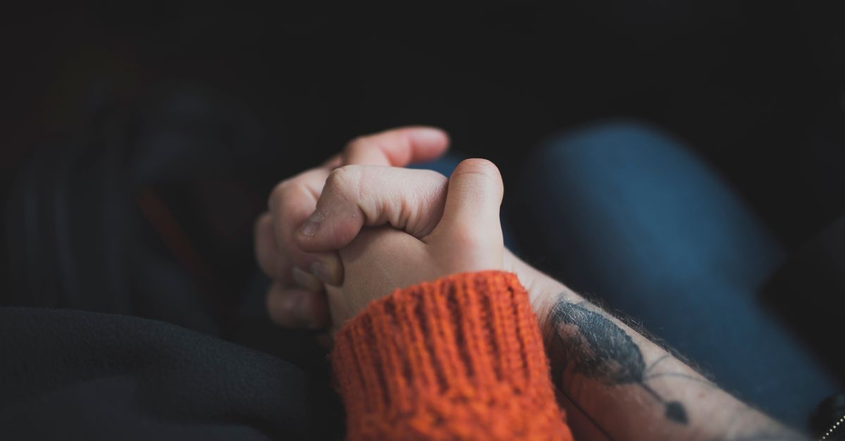 Two hands holding each other, symbolizing love and support with a warm tone.