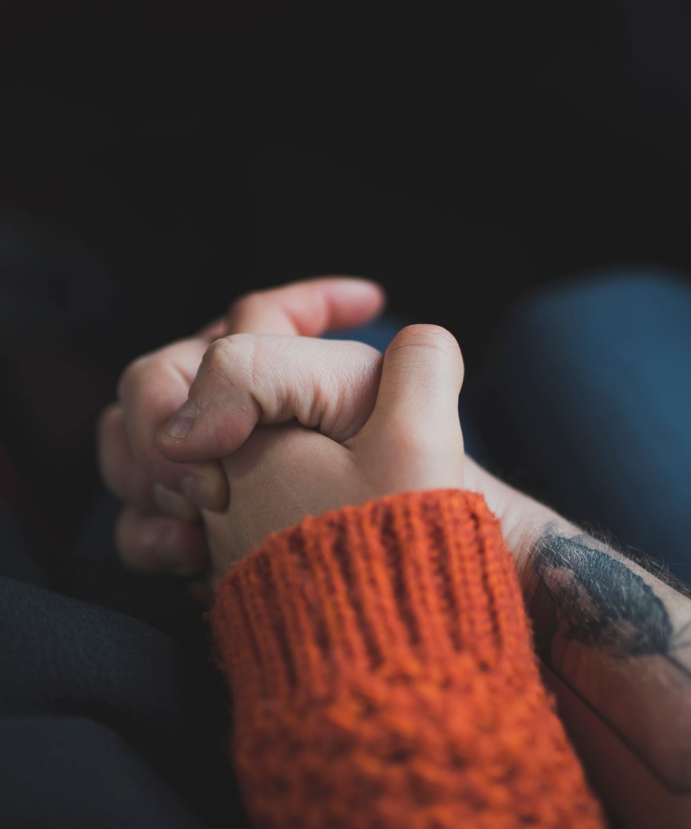 Two hands holding each other gently in warm sunset light