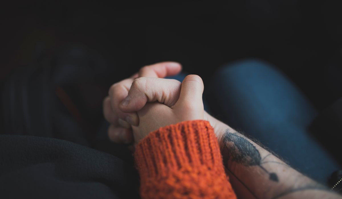 Two hands holding each other in warm light