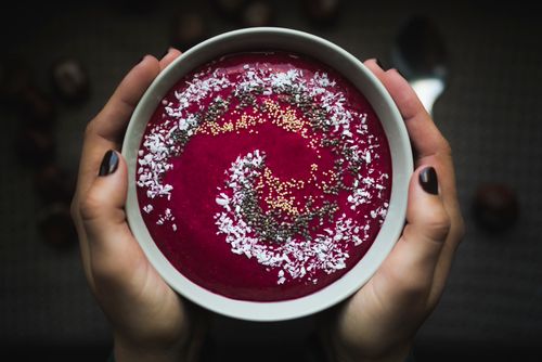 Free A vibrant berry bowl topped with coconut flakes and seeds held in hands. Stock Photo
