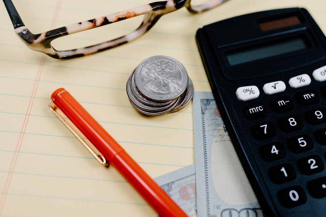 Free Calculator, Red Pen and Coins on Notepad Stock Photo